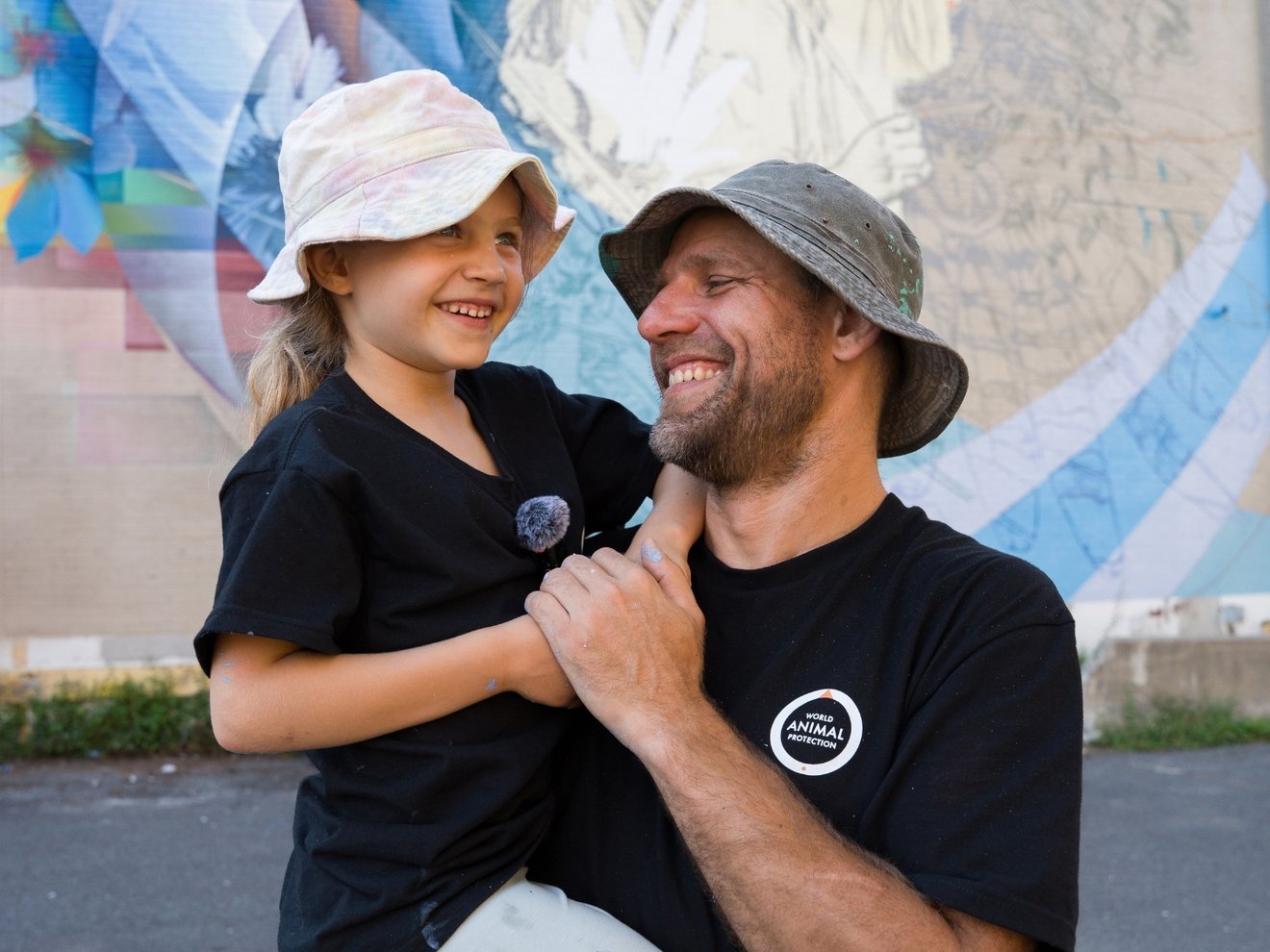 Fluke holding his daughter in front of mural