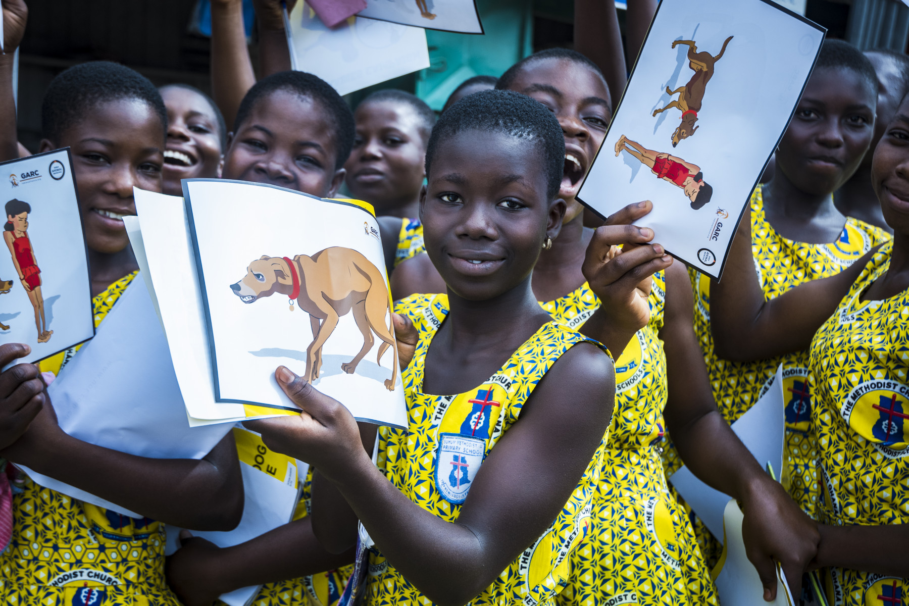 Children holding up a World Animal Protection book about dogs