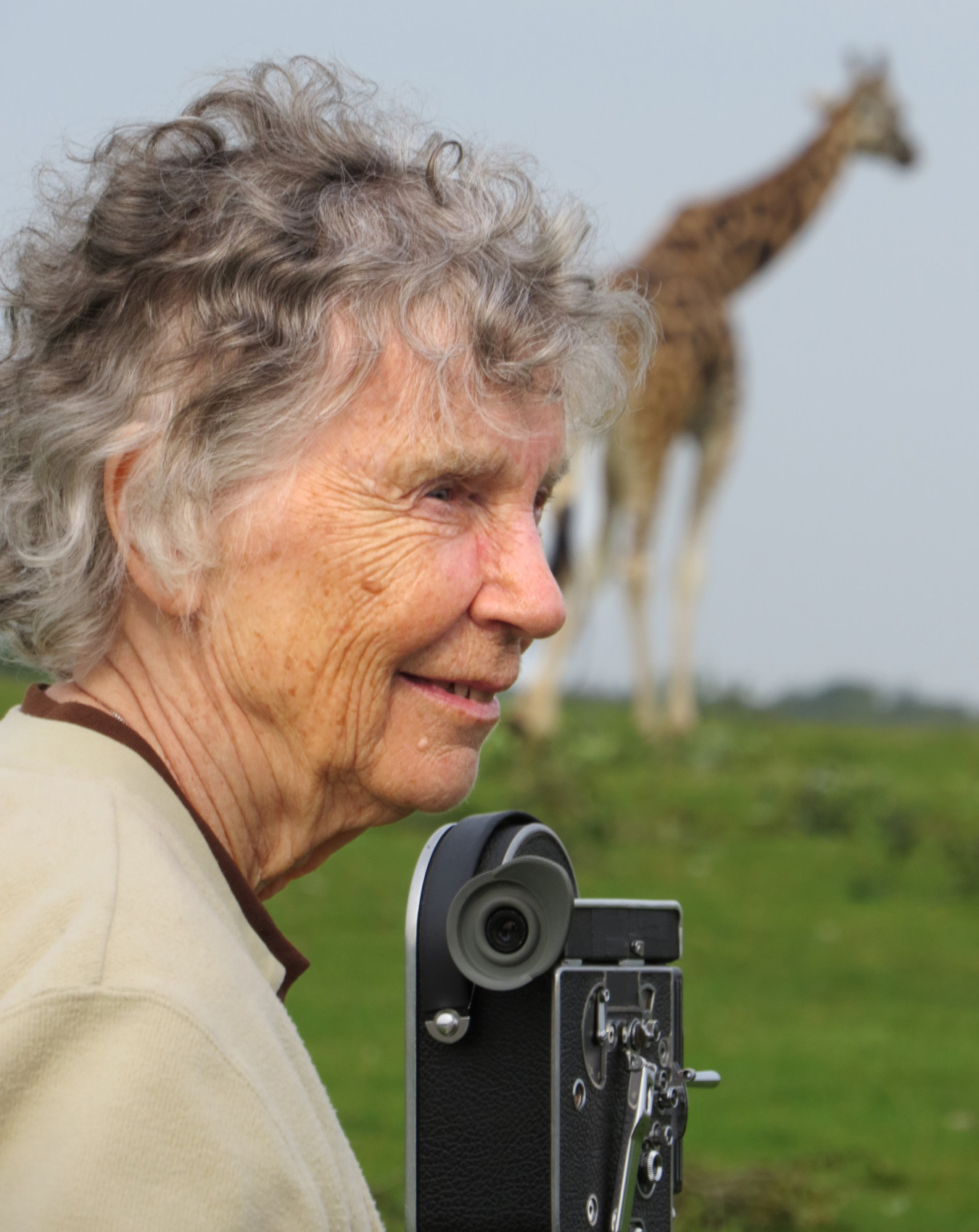Dr. Dagg with a camera and giraffe